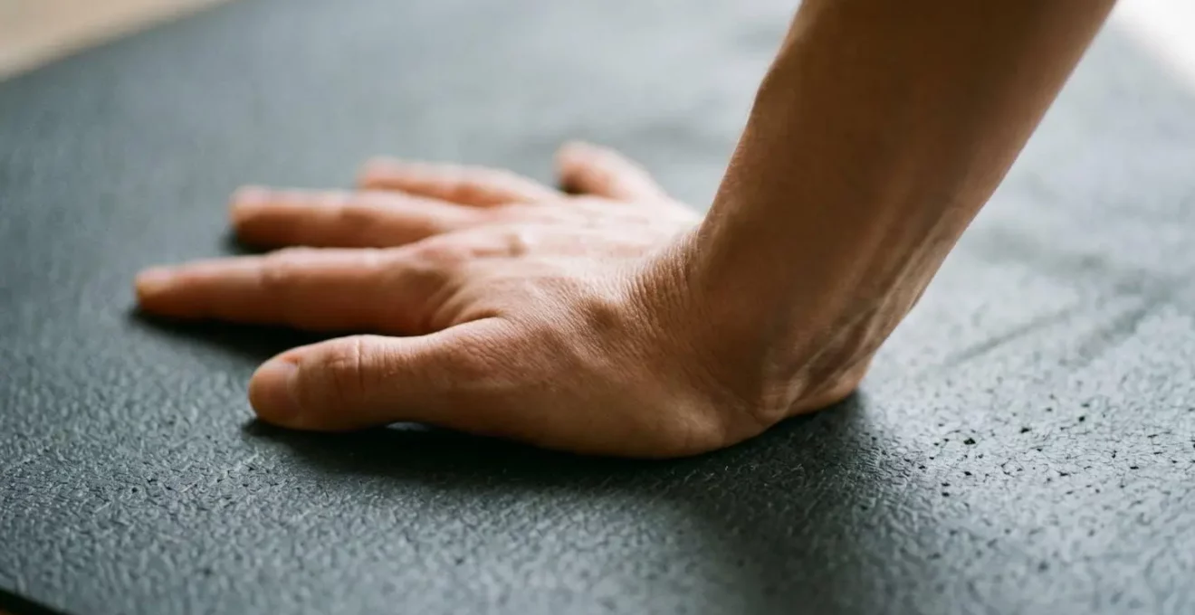 Vue rapprochée des mains en appui au sol lors d'une posture de yoga, mettant en évidence la biomécanique correcte du poignet
