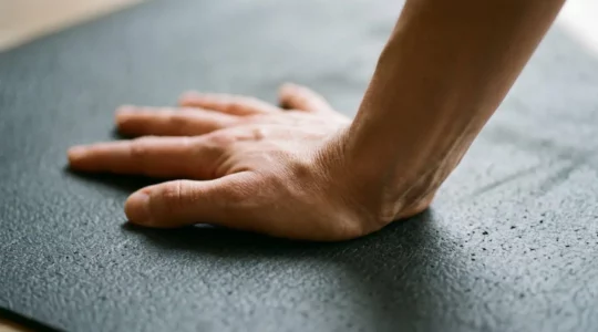 Vue rapprochée des mains en appui au sol lors d'une posture de yoga, mettant en évidence la biomécanique correcte du poignet