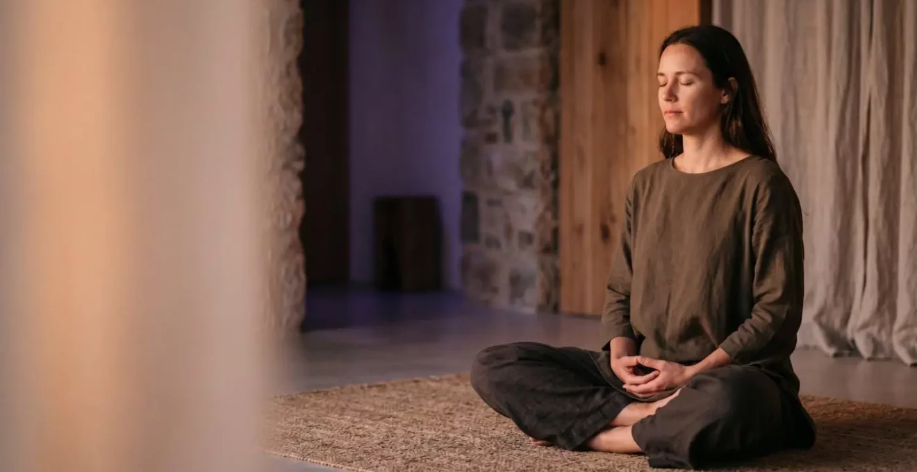 Personne en posture de méditation dans un espace épuré illustrant la pratique du yoga Kundalini avec symbolisme énergétique